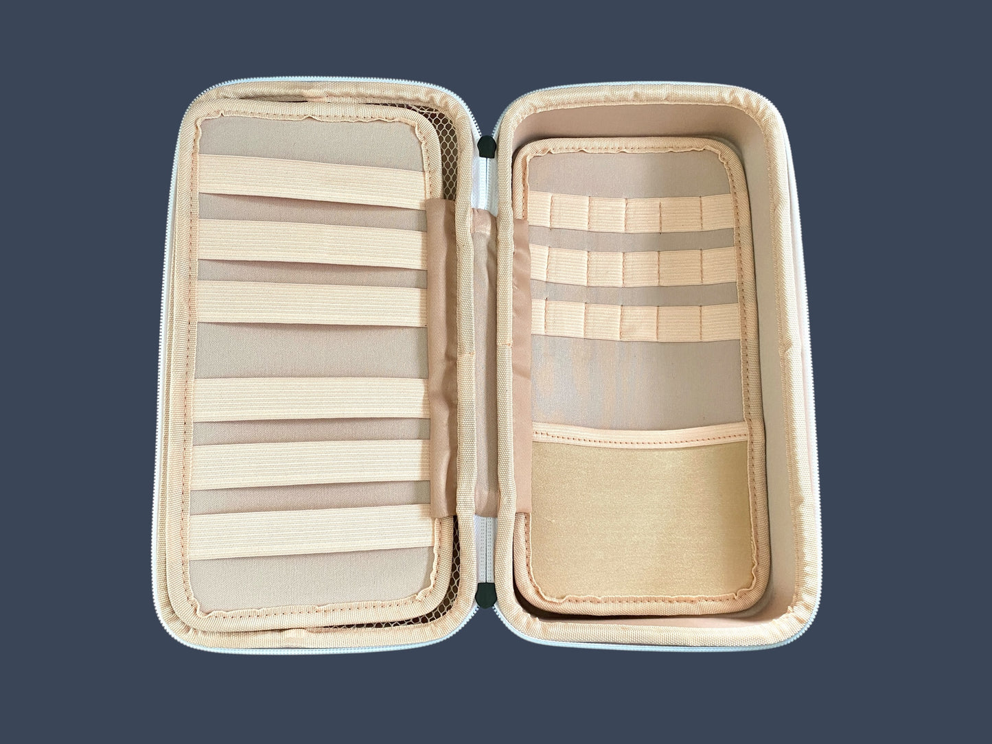 Open beige jewelry case with compartments on a dark blue background